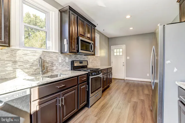 a kitchen with stainless steel appliances granite countertop a stove a sink and a microwave