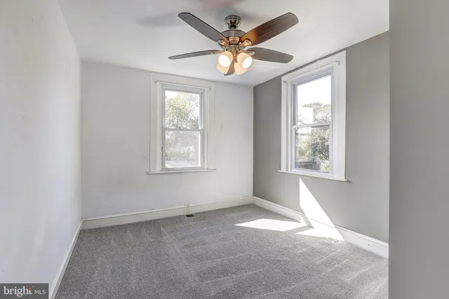 an empty room with windows and ceiling fan