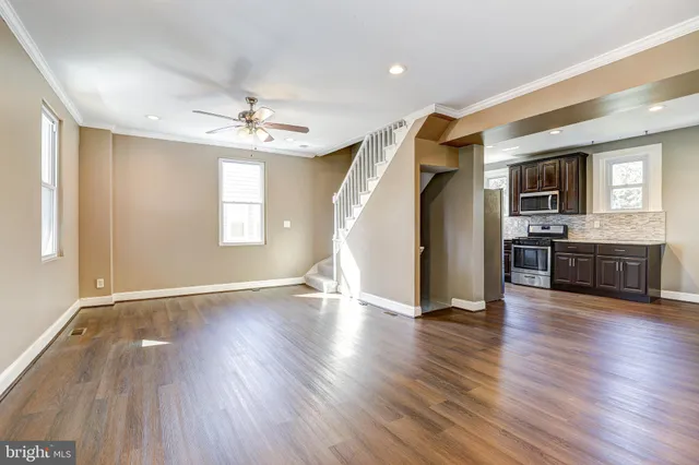 a view of an empty room with window and wooden floor