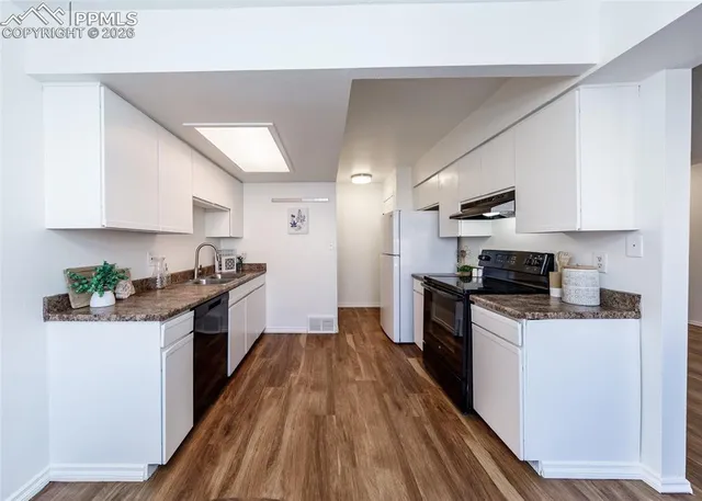 a kitchen with granite countertop a stove top oven a sink dishwasher and a refrigerator with wooden floor