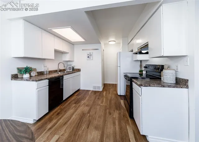 a kitchen with granite countertop wooden floors and white stainless steel appliances