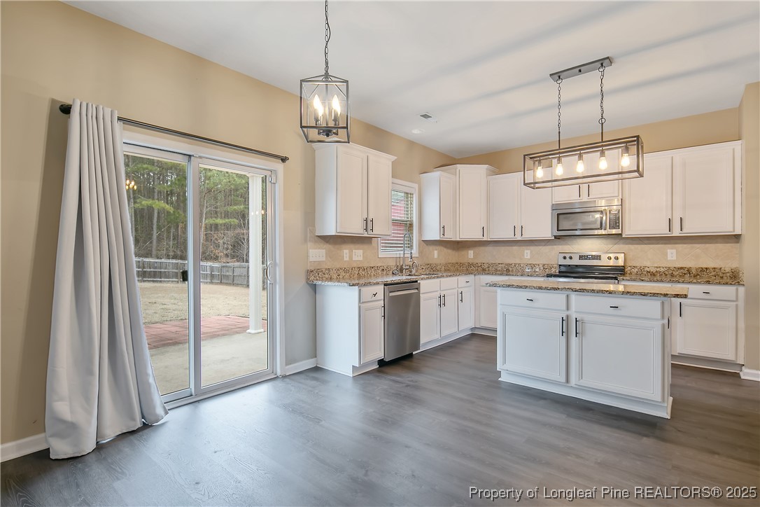 4964 Aberdeen Road Raeford, NC 28376 - Photo 14 of 50 a kitchen with kitchen island granite countertop a stove a sink a center island a refrigerator and a view of living room
