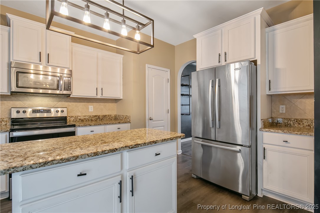 4964 Aberdeen Road Raeford, NC 28376 - Photo 17 of 50 a kitchen with granite countertop a refrigerator stove and microwave