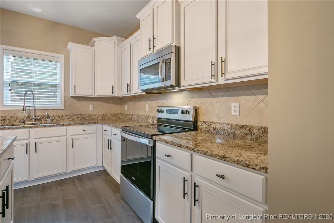 4964 Aberdeen Road Raeford, NC 28376 - Photo 18 of 50 a kitchen with granite countertop white cabinets and white stainless steel appliances