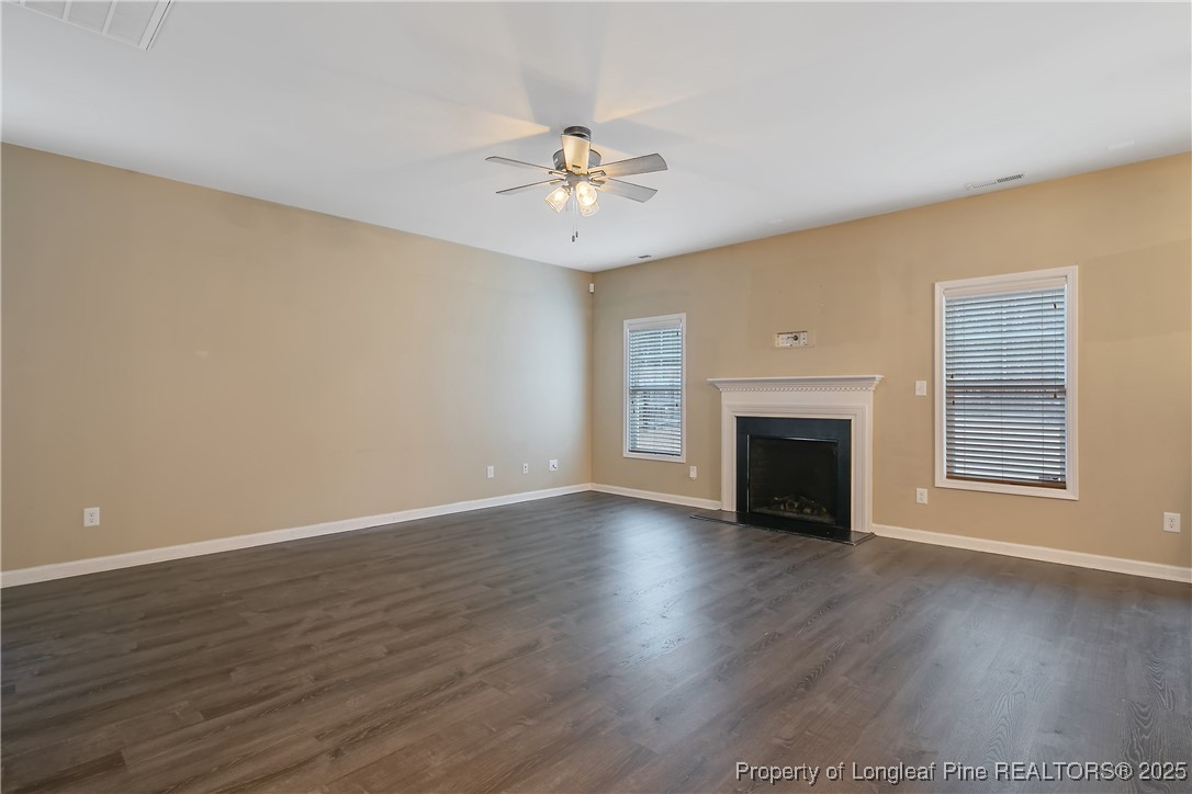4964 Aberdeen Road Raeford, NC 28376 - Photo 10 of 50 an empty room with wooden floor fireplace and fan
