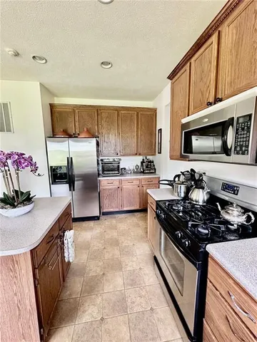 a kitchen with stainless steel appliances a stove a sink a microwave a refrigerator and cabinets