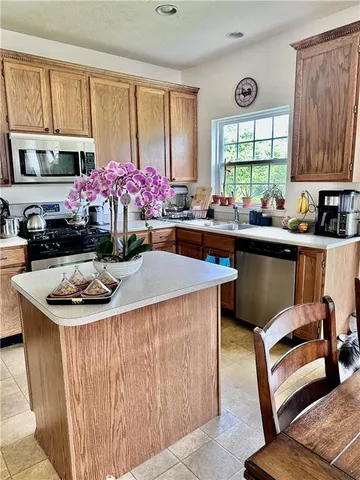 a kitchen with a stove a sink dishwasher and a dining table with wooden cabinet
