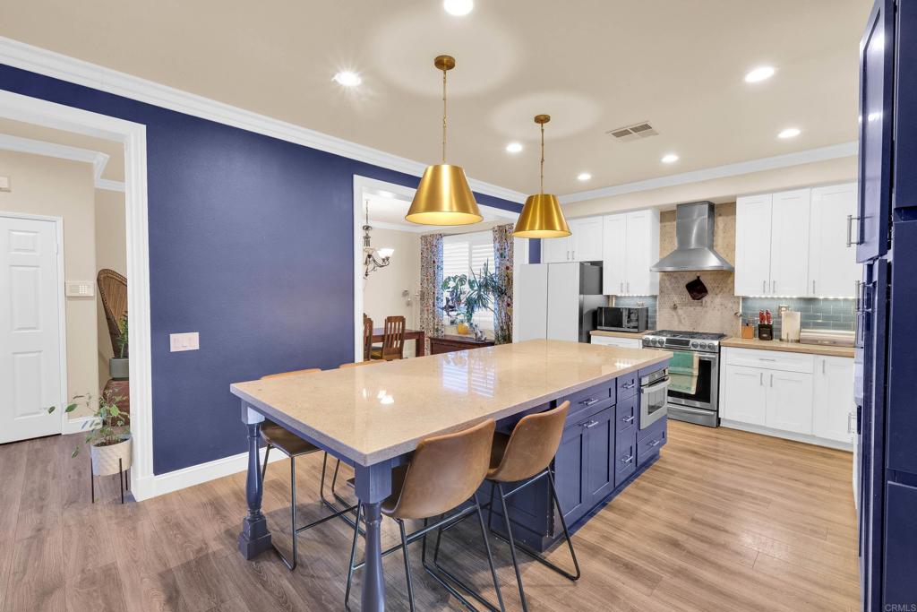 8359 Clover Creek Road Riverside, CA 92508 - Photo 11 of 42 a kitchen with stainless steel appliances granite countertop a kitchen island hardwood floor sink stove dining table and chairs