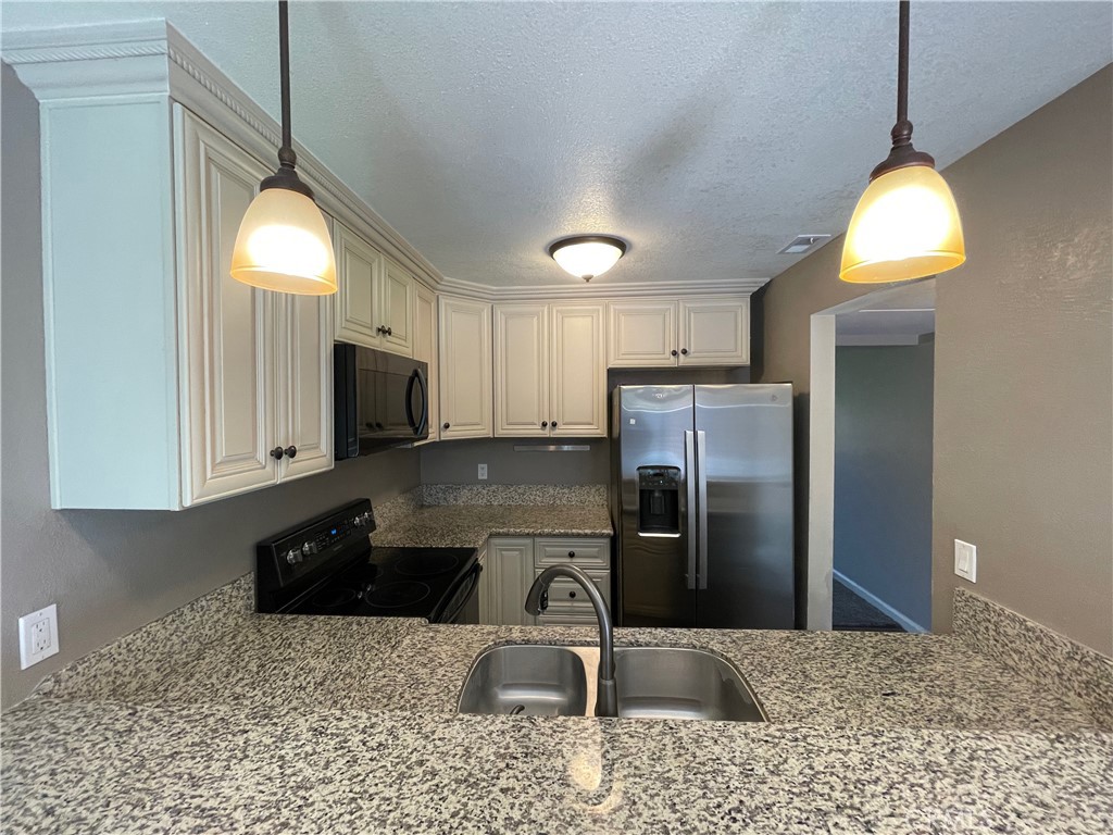 979 West Pine Street Upland, CA 91786 - Photo 6 of 18 a kitchen with a sink a counter top space cabinets and stainless steel appliances