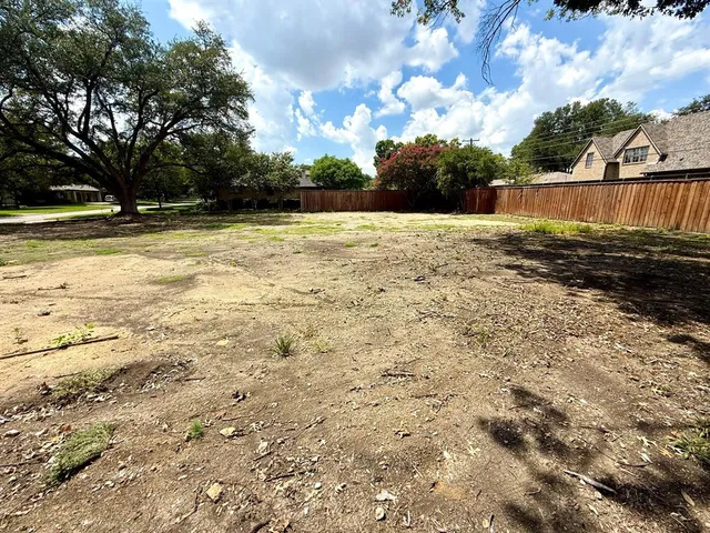 a view of swimming pool with large tree and wooden fence