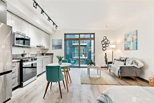a living room with stainless steel appliances furniture and a kitchen view