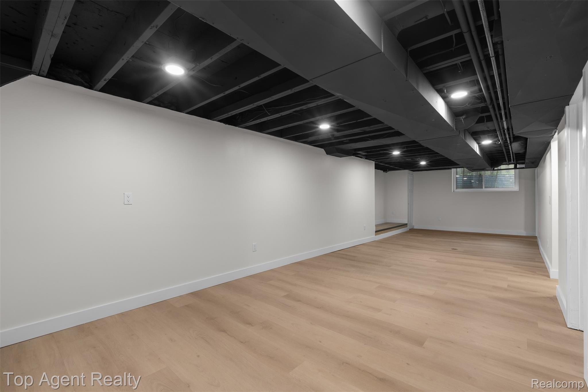 29863 Fall River Road Southfield, MI 48076 - Photo 26 of 50 Spacious room featuring light wood-finish flooring, white walls, and a dark exposed ceiling with recessed lighting