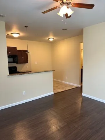 a view of a room with a ceiling fan and wooden floor