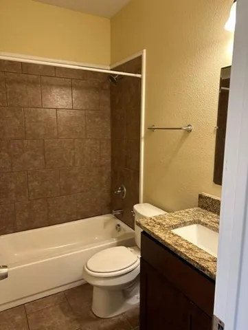 a bathroom with a granite countertop bathtub shower sink vanity and toilet