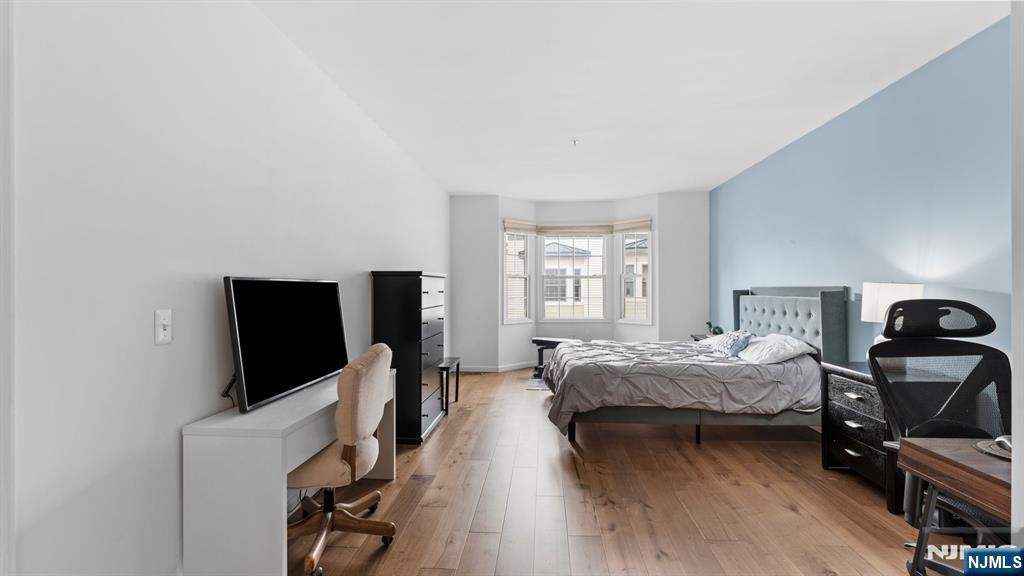 344 The Promenade, Unit 344 Edgewater, NJ 07020 - Photo 23 of 44 a bedroom with a bed and a flat tv screen on a dresser