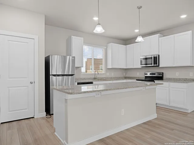 a kitchen with stainless steel appliances granite countertop a sink and a refrigerator