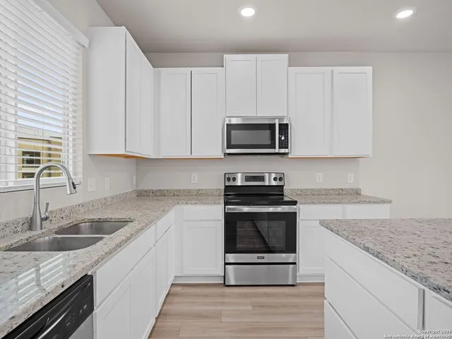 a kitchen with granite countertop a stove sink and microwave