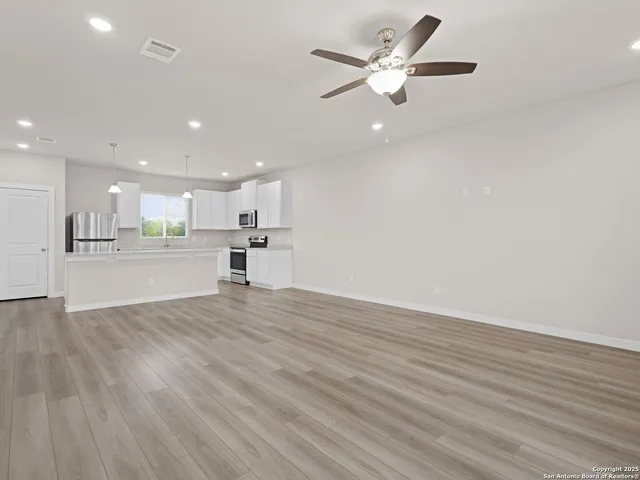 a view of an empty room with wooden floor and windows