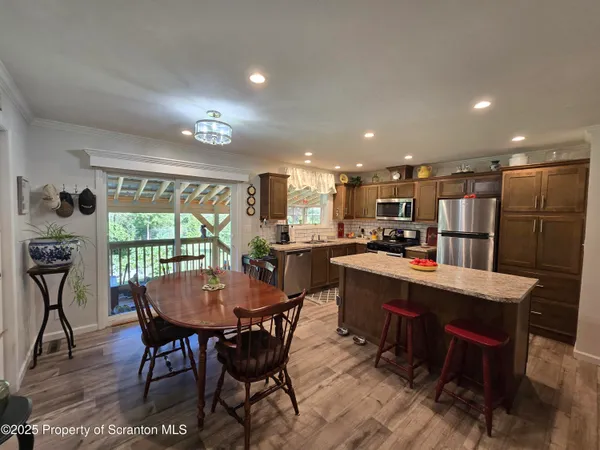 a dining room with stainless steel appliances kitchen island granite countertop a dining table chairs and a refrigerator