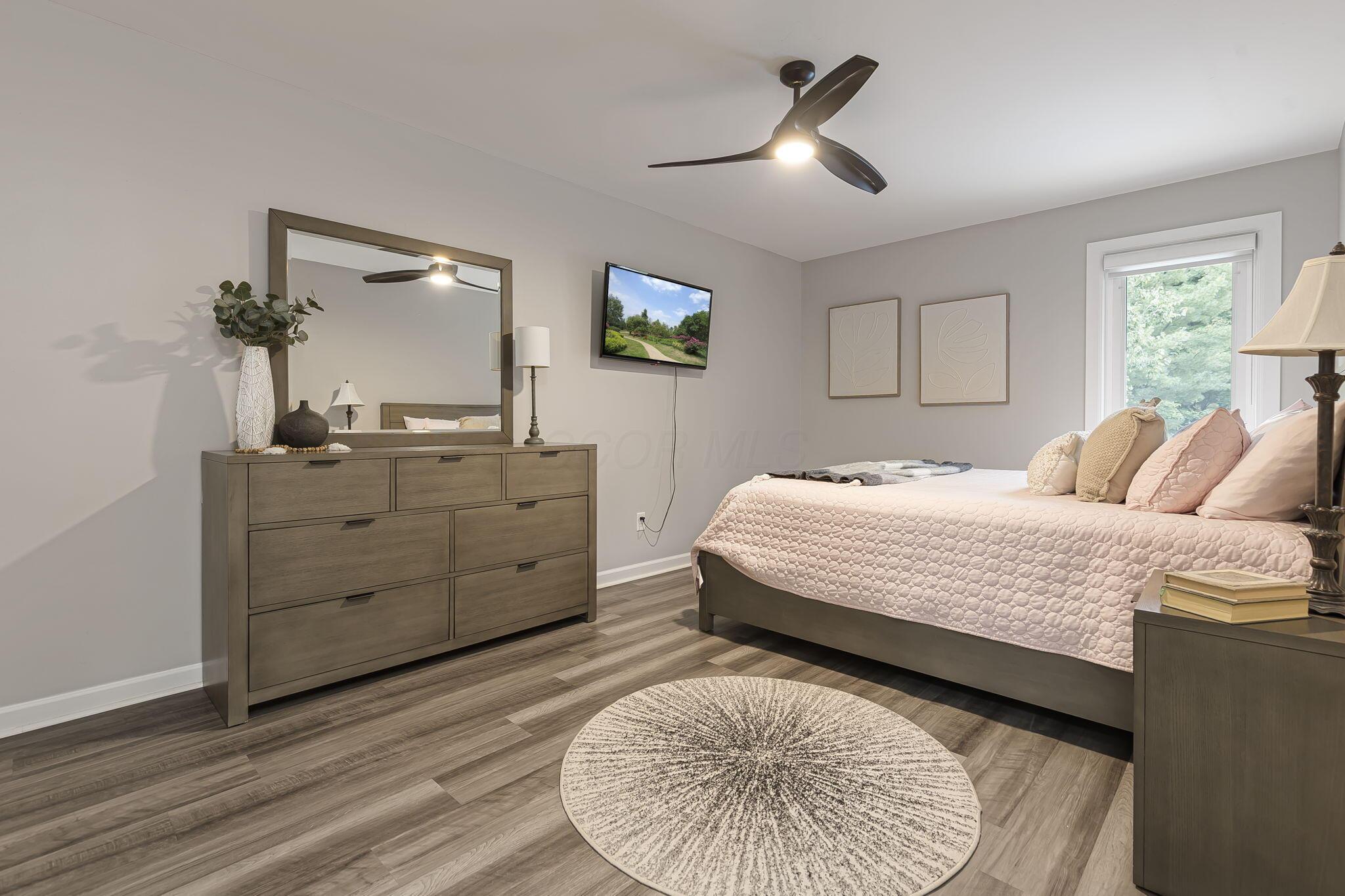 7140 Cook Road Powell, OH 43065 - Photo 52 of 87 Spacious primary bedroom showcasing wood-finish flooring, a ceiling fan with integrated lighting, and large windows providing natural light