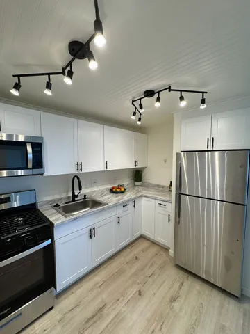 a kitchen with a sink stainless steel appliances and wooden floor