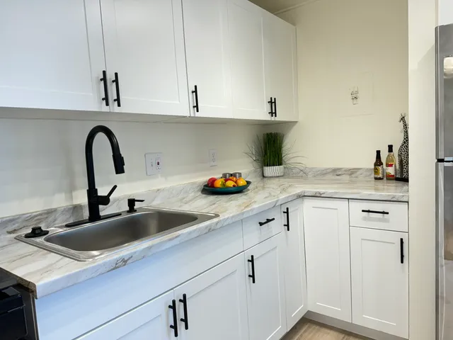 a kitchen with white cabinets a sink and wooden floor