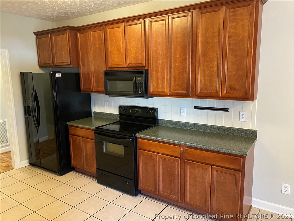 3532 Talus Road Fayetteville, NC 28306 - Photo 16 of 34 a kitchen with granite countertop a refrigerator stove and cabinets