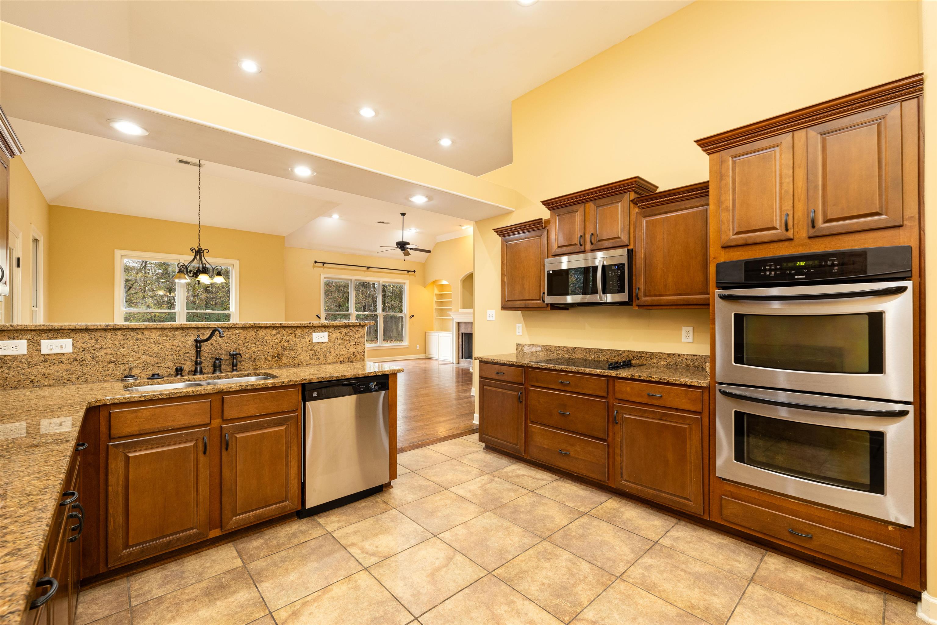 5380 Scarlet Ridge Drive Arlington, TN 38002 - Photo 14 of 30 Kitchen with appliances with stainless steel finishes, a chandelier, brown cabinets, ceiling fan, and light stone countertops