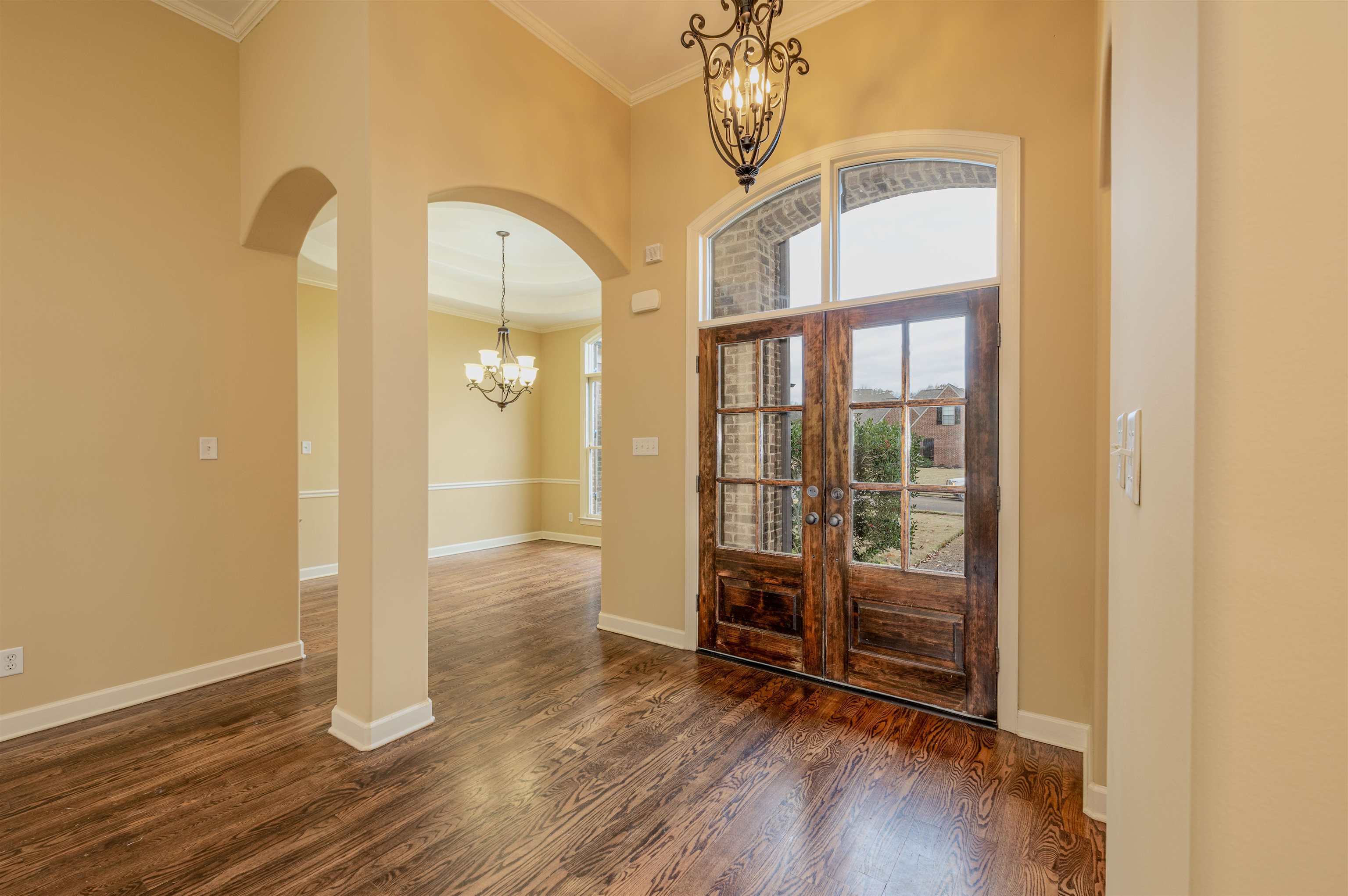 5380 Scarlet Ridge Drive Arlington, TN 38002 - Photo 4 of 30 Entryway featuring a chandelier, arched walkways, ornamental molding, dark wood-type flooring, and a towering ceiling