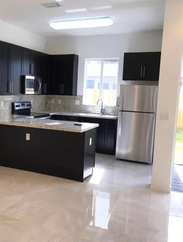 a kitchen with stainless steel appliances granite countertop a refrigerator a sink a stove a microwave and wooden cabinets