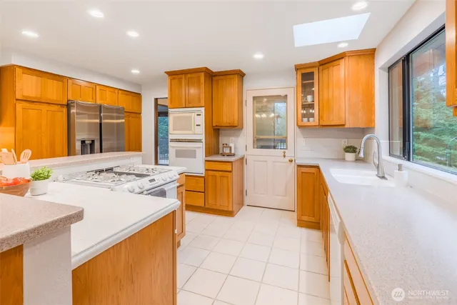 a view of a kitchen with kitchen island a large window cabinets a sink and a counter top space