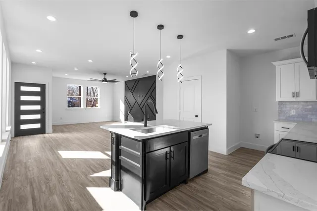 a view of a kitchen with kitchen island a sink wooden floor and a living room view