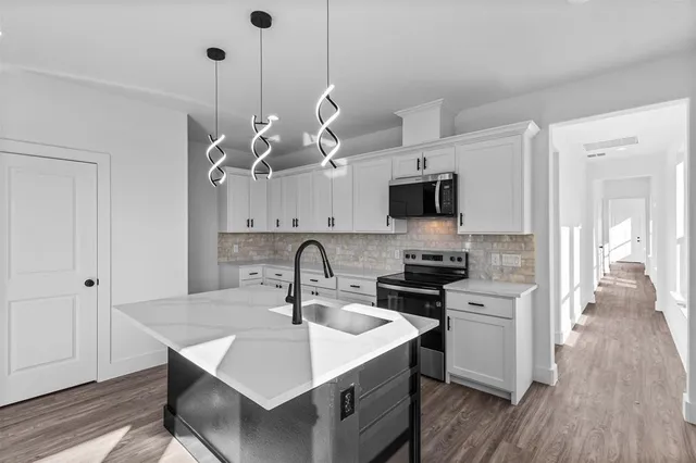 a kitchen with kitchen island a sink stainless steel appliances and wooden floor