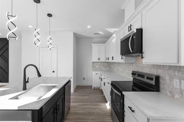 a kitchen with stainless steel appliances granite countertop a sink a stove top oven a counter space and cabinets