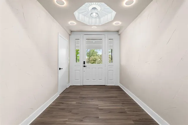 a view of an empty room with wooden floor and window