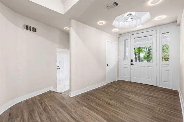 an empty room with wooden floor and windows