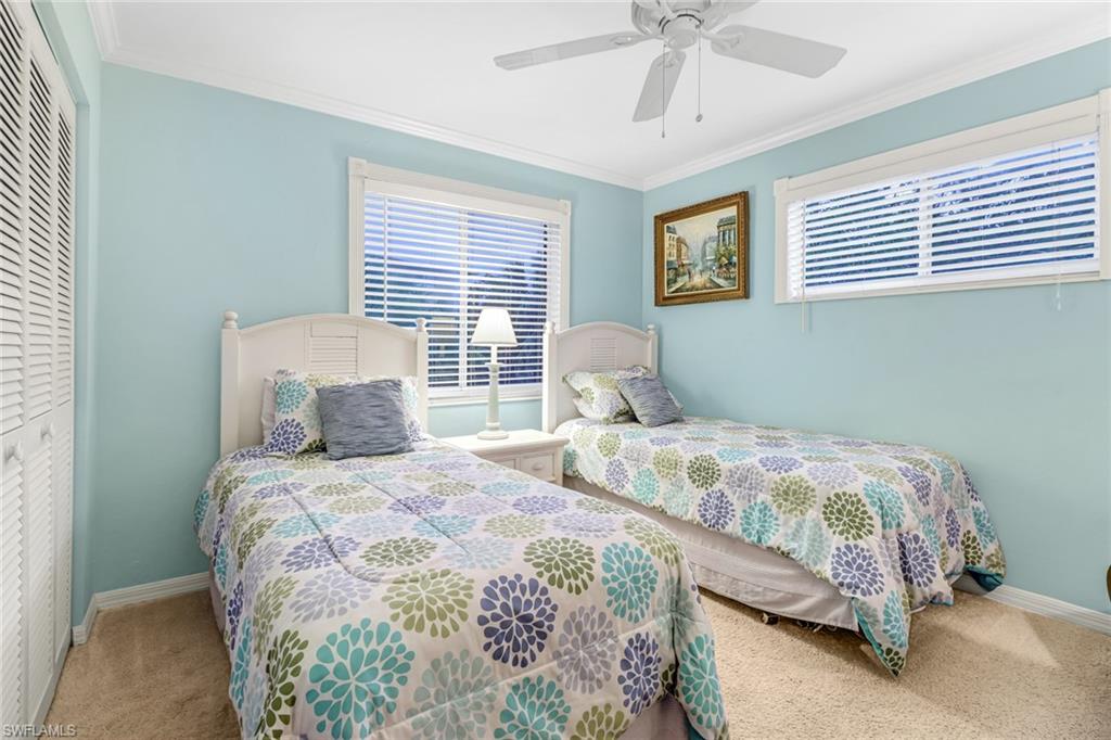 3041 Sandpiper Bay Circle, Unit H201 Naples, FL 34112 - Photo 20 of 25 Carpeted bedroom featuring crown molding, a closet, multiple windows, and a ceiling fan