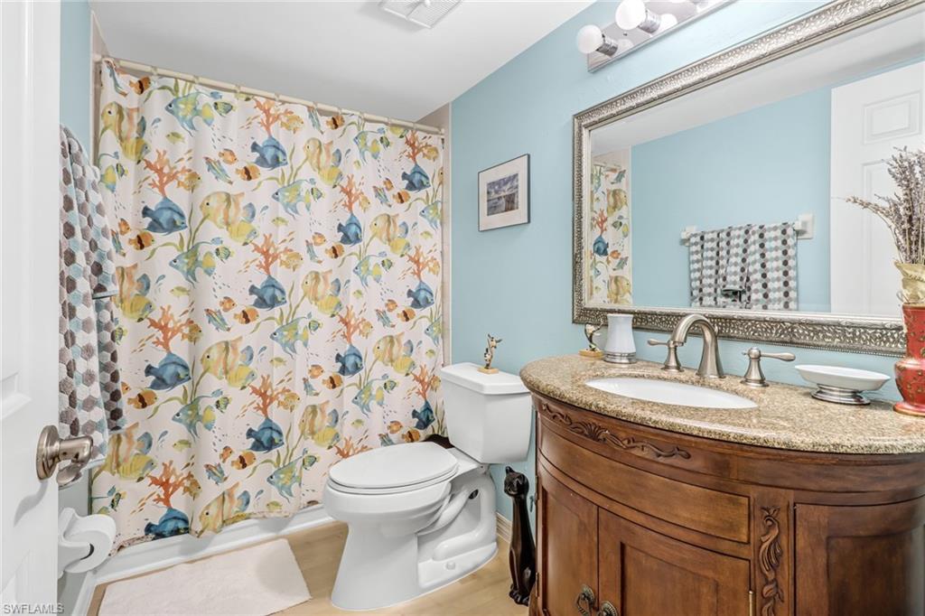 3041 Sandpiper Bay Circle, Unit H201 Naples, FL 34112 - Photo 21 of 25 Bathroom with vanity, shower / tub combo with curtain, and wood finished floors