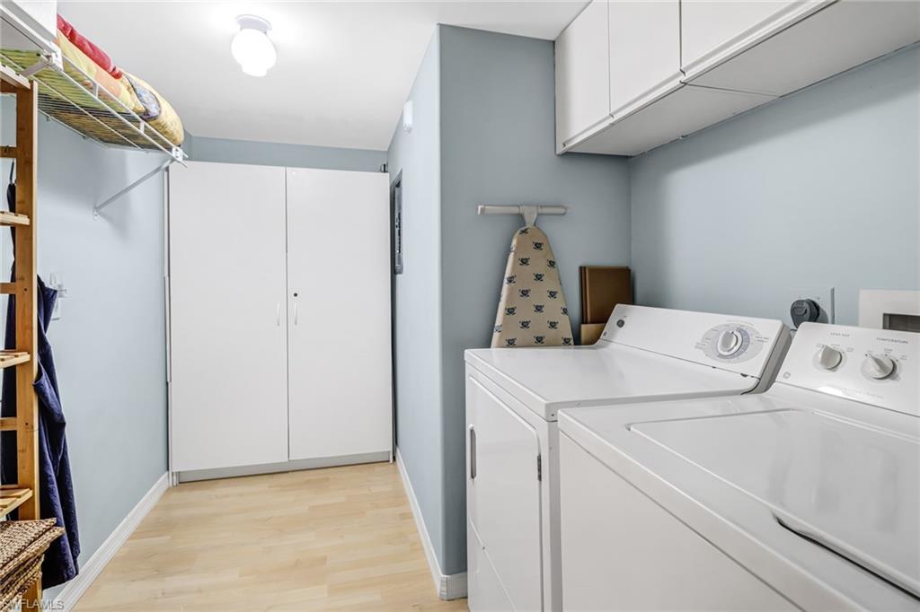 3041 Sandpiper Bay Circle, Unit H201 Naples, FL 34112 - Photo 25 of 25 Washroom with cabinet space, light wood-style flooring, and washing machine and clothes dryer
