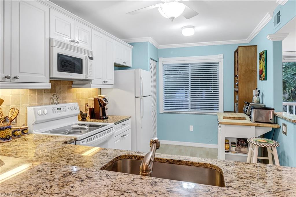 3041 Sandpiper Bay Circle, Unit H201 Naples, FL 34112 - Photo 3 of 25 Kitchen featuring crown molding, white appliances, white cabinets, a ceiling fan, and decorative backsplash