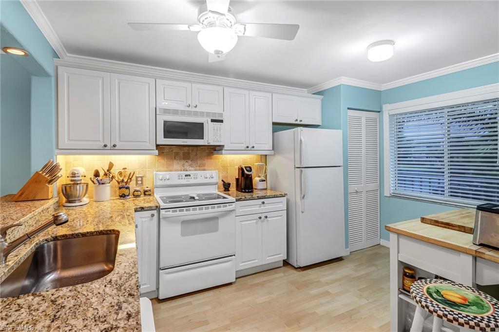 3041 Sandpiper Bay Circle, Unit H201 Naples, FL 34112 - Photo 6 of 25 Kitchen with white appliances, white cabinetry, backsplash, crown molding, and light wood-style floors