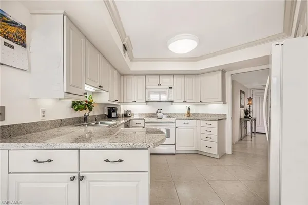 a kitchen with granite countertop white cabinets white appliances and granite counter tops
