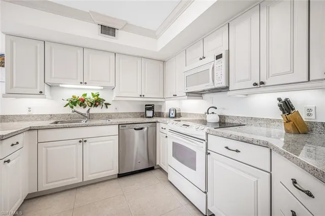 a kitchen with granite countertop white cabinets white appliances and sink