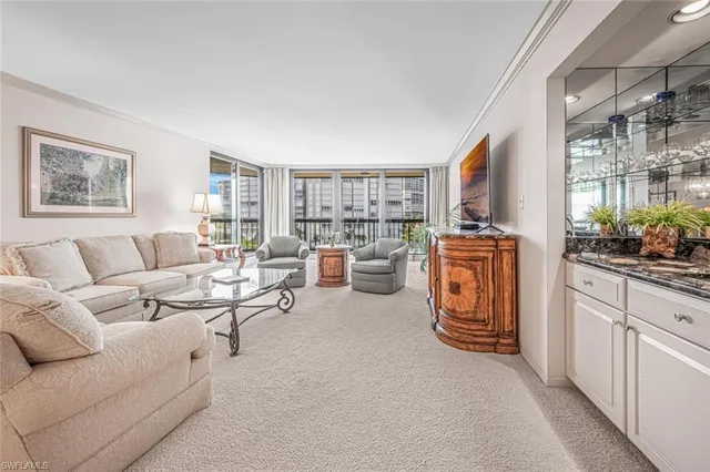 a living room with furniture a large window and kitchen view