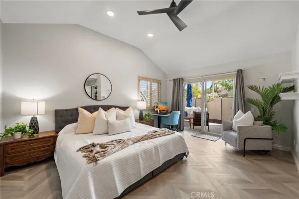 a bedroom with a bed couch chandelier and windows