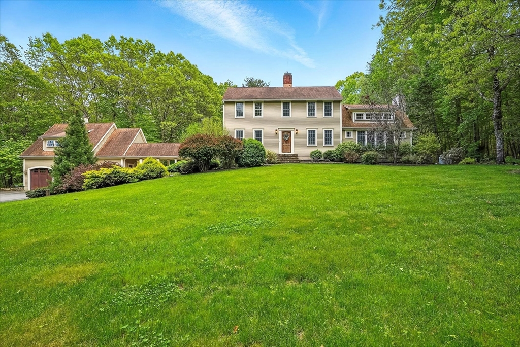 a view of a house next to a big yard and large trees