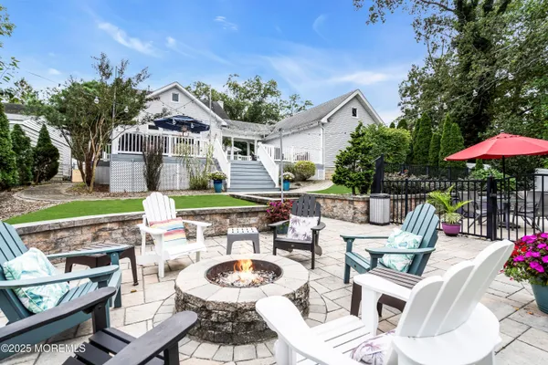 a view of a patio with couches table and chairs under an umbrella with a fire pit