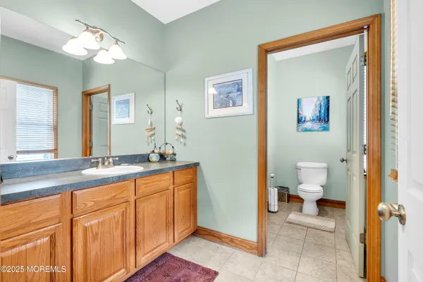 a spacious bathroom with a granite countertop sink a toilet and a mirror
