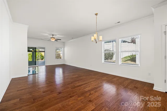 a view of an empty room with window and wooden floor