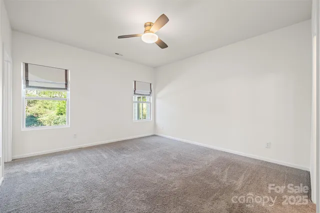 an empty room with ceiling fan and window